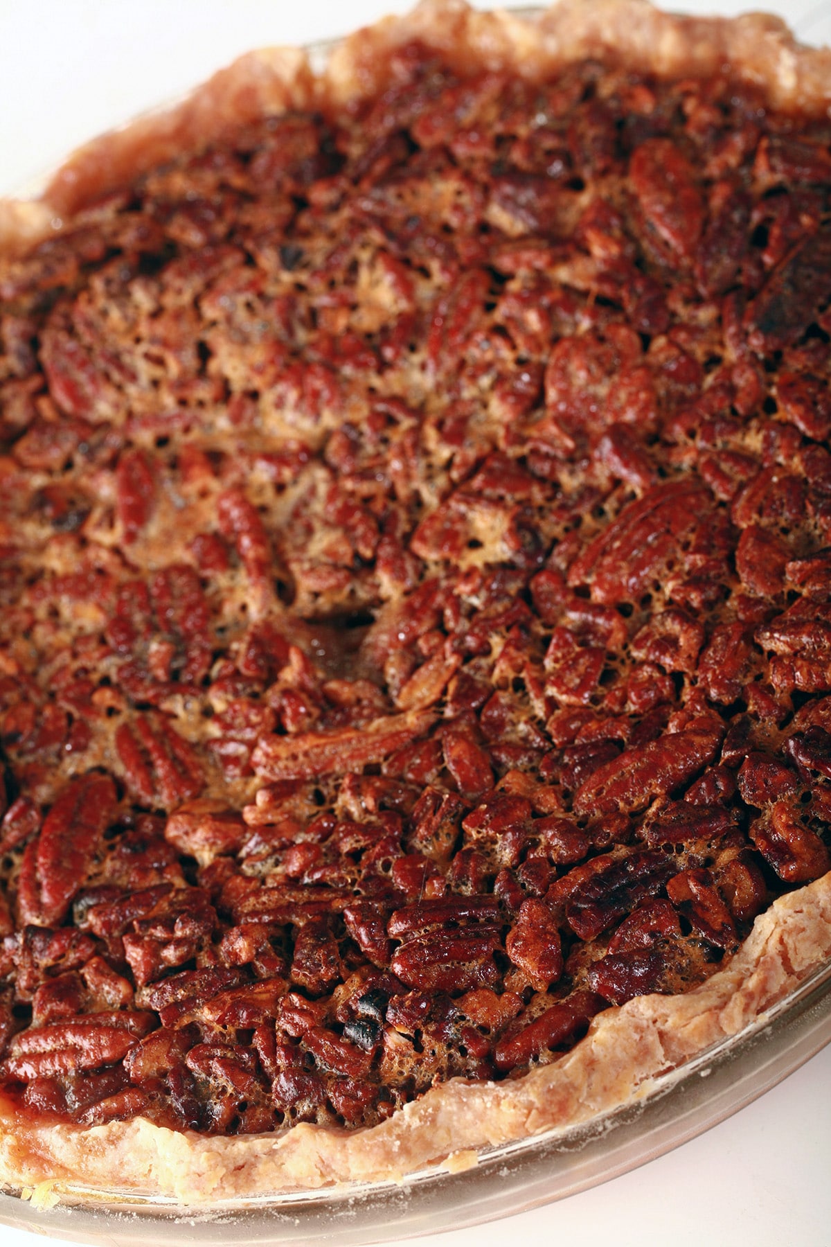 A close up view of a whole, uncut Southern Comfort Pecan Pie.