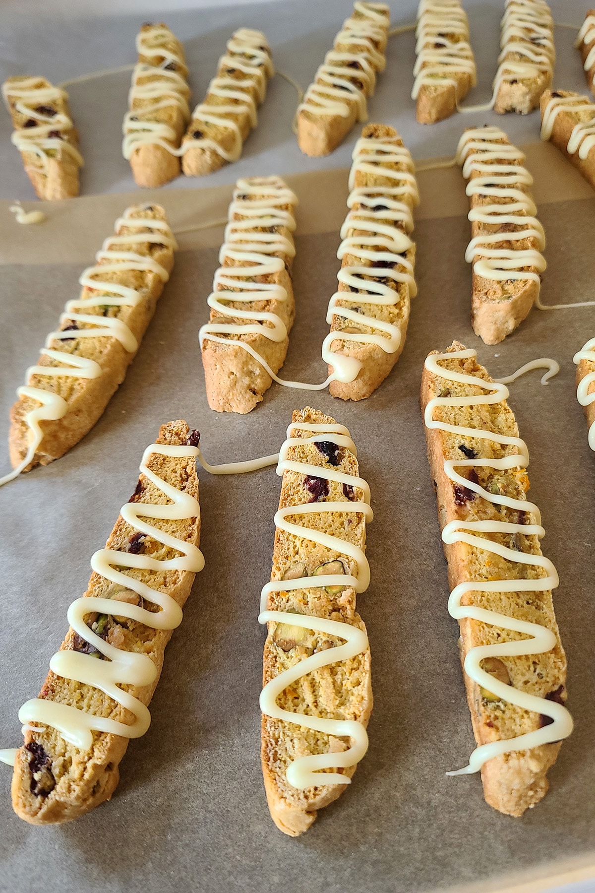A close up view of the drizzled biscotti arranged on parchment.