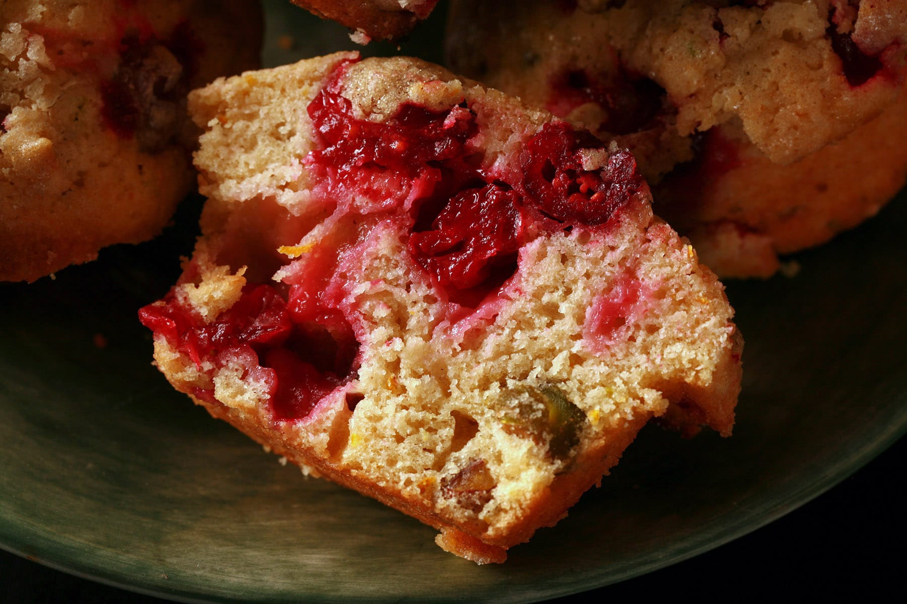 A plate with several cranberry orange pistachio muffins.