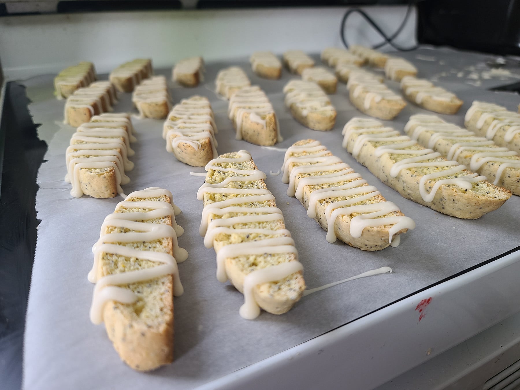 A close up view of the glazed biscotti drying on the parchment lined stovetop.