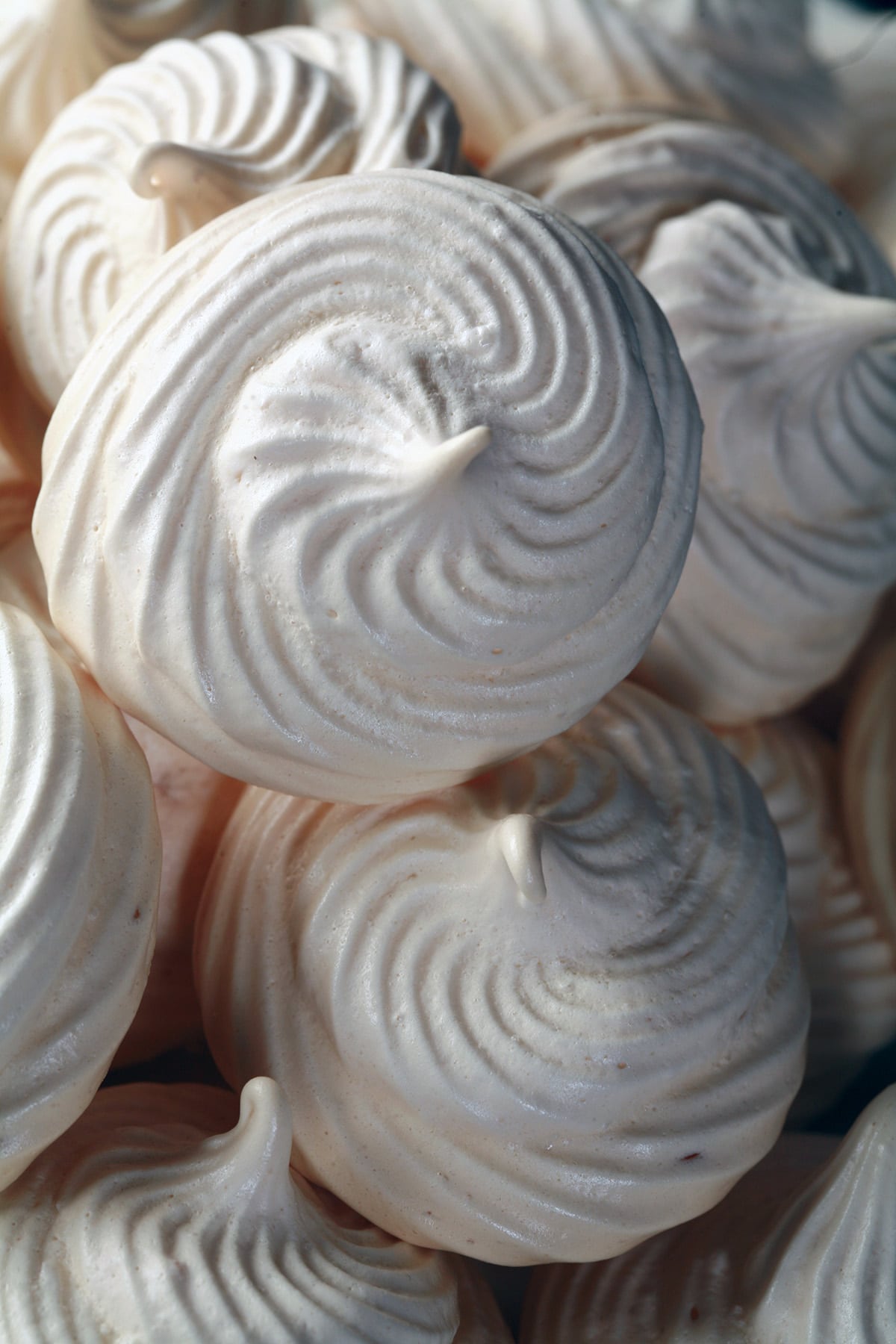 A plate piled high with swirl shaped malted milk meringue cookies.