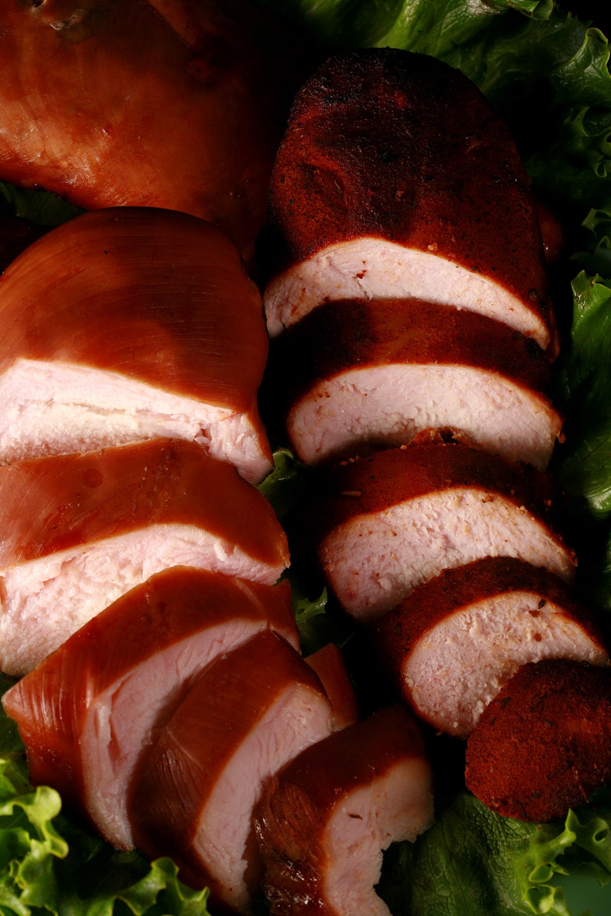 Several sliced smoked chicken breasts on a platter of lettuce.