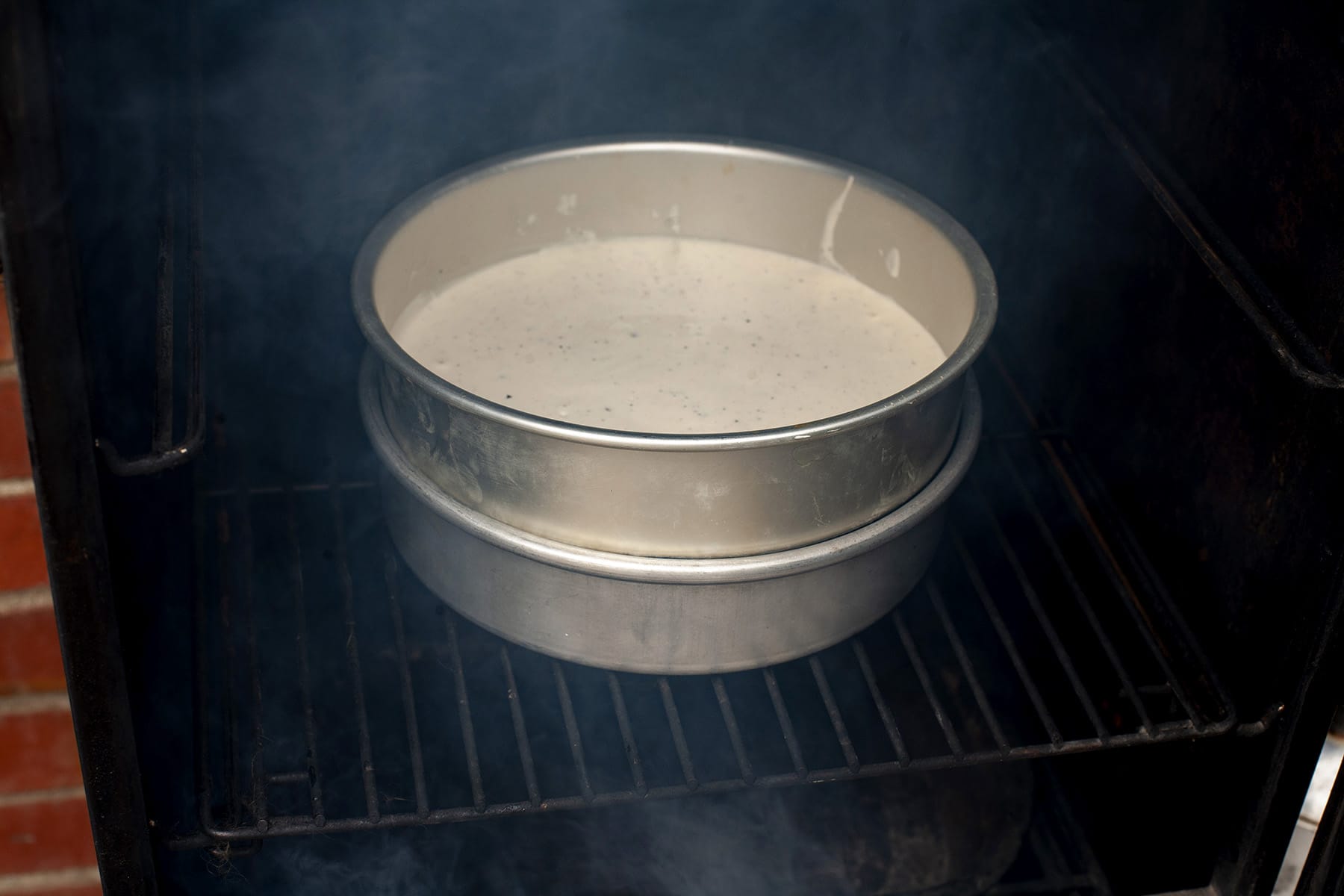 A round cake pan of mayo resting on another round cake pan that's full of ice.