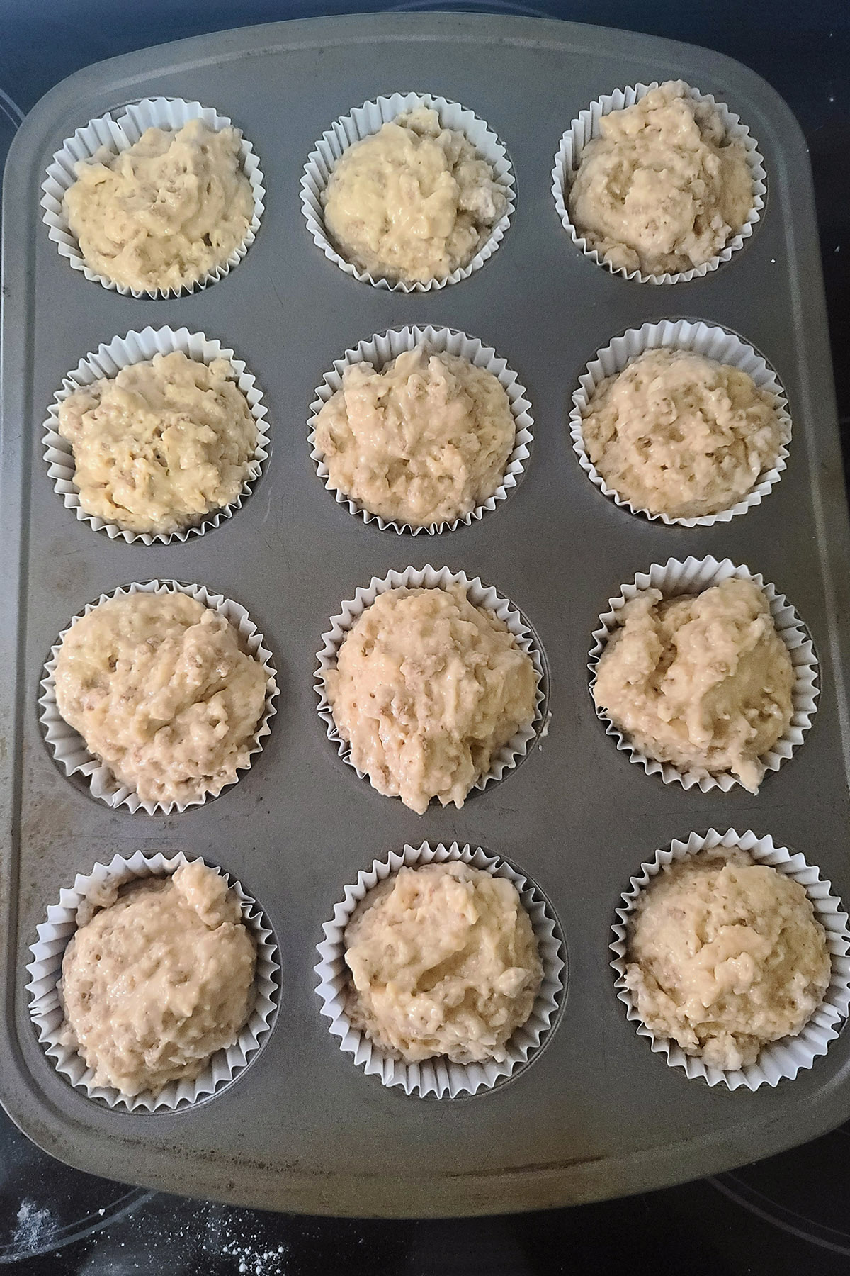 A muffin pan filled with all-bran muffins batter.