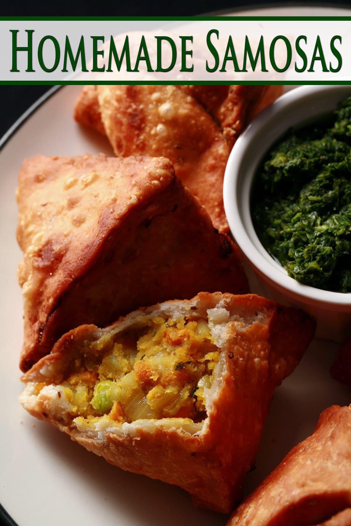 A plate of homemade samosas, with a small bowl of cilantro mint chutney.
