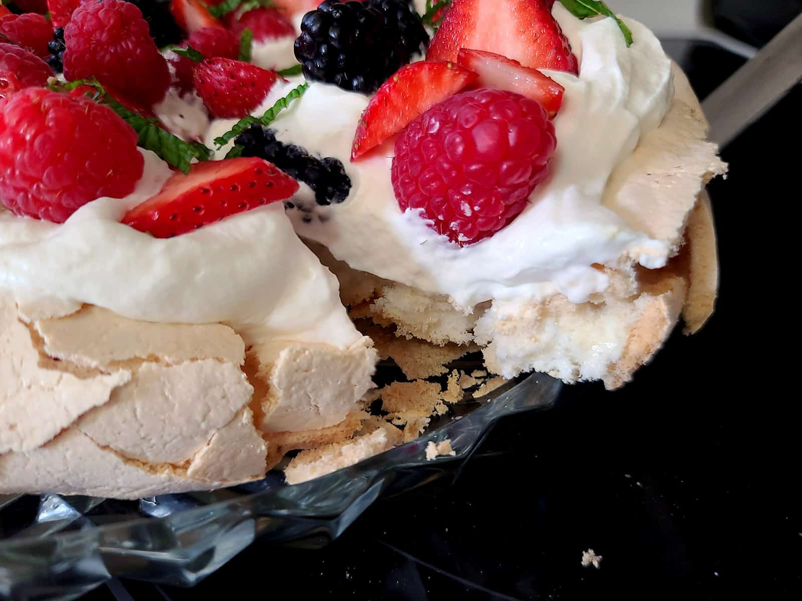 A close up photo of a slice of pavlova being lifted from the serving plate.