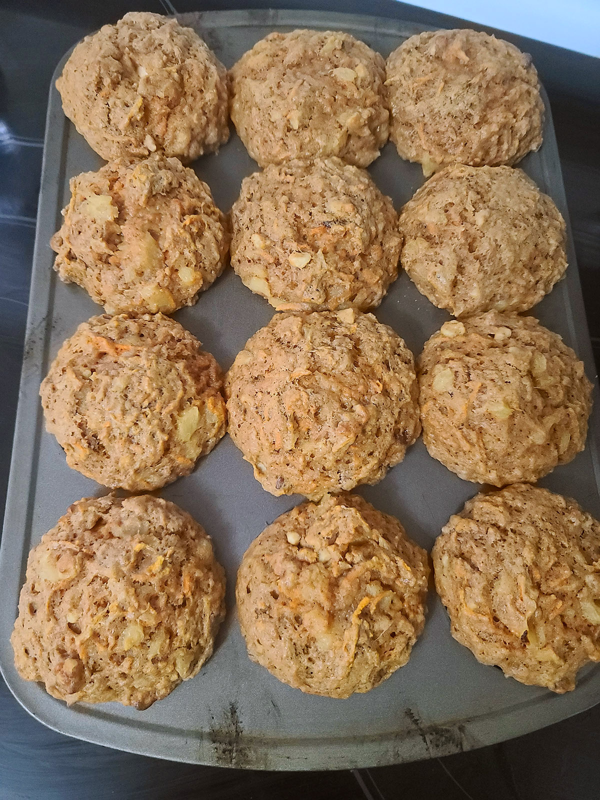 A pan of 12 carrot cake muffins, fresh from the oven.