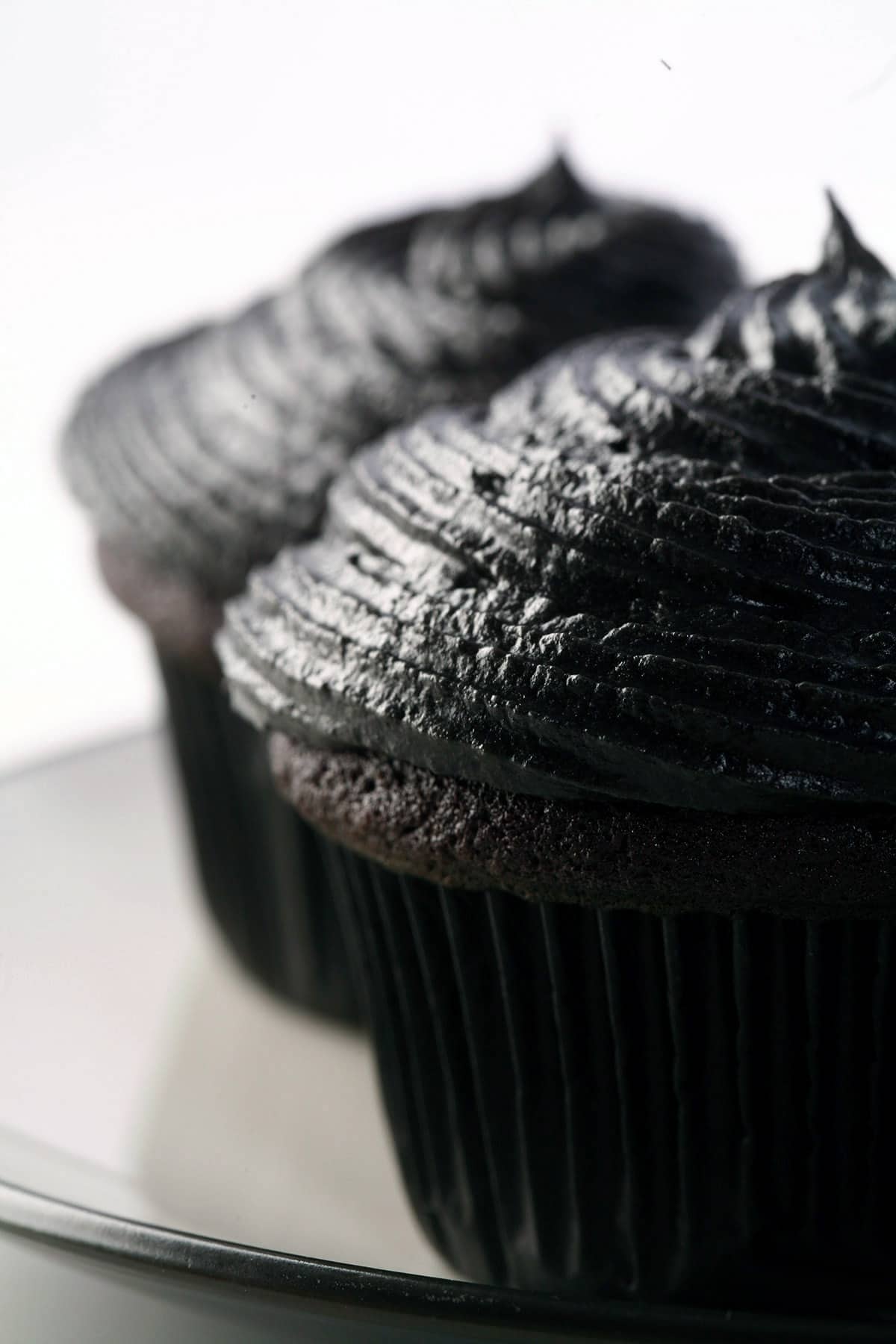 2 black velvet cupcakes on a white plate.