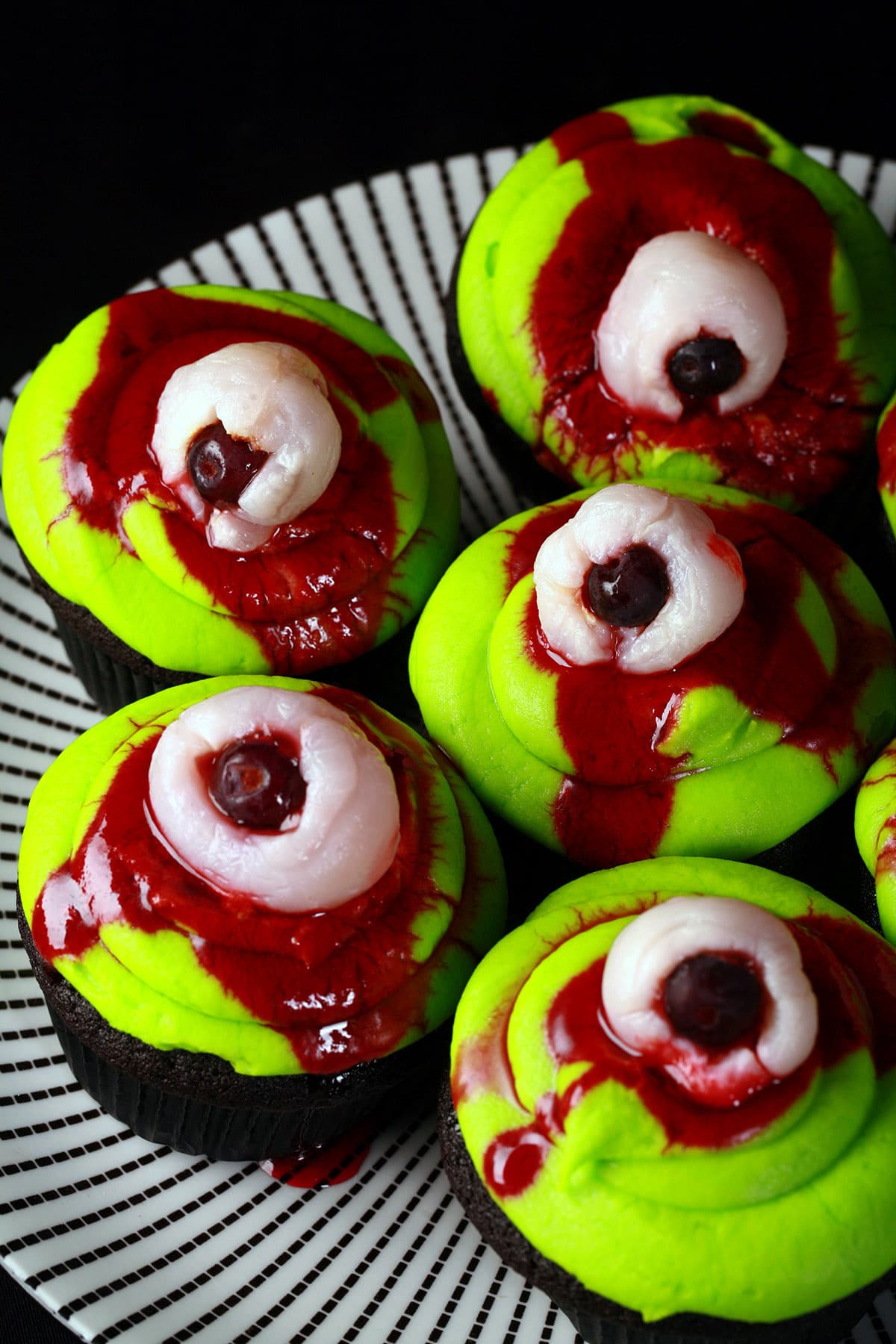 Several lychee bloody eyeball cupcakes on a plate.