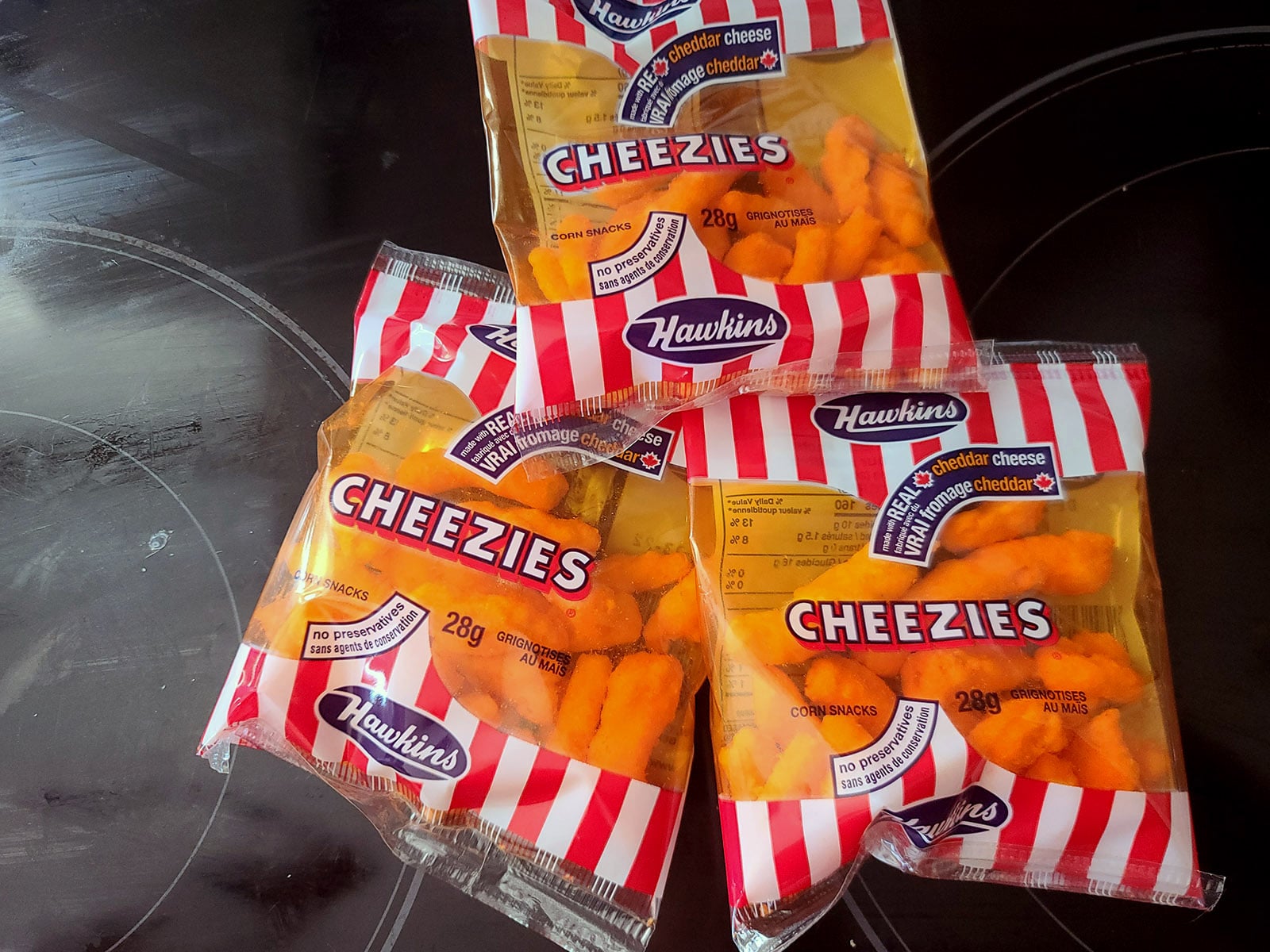 3 snack size bags of cheezies on a stove top.