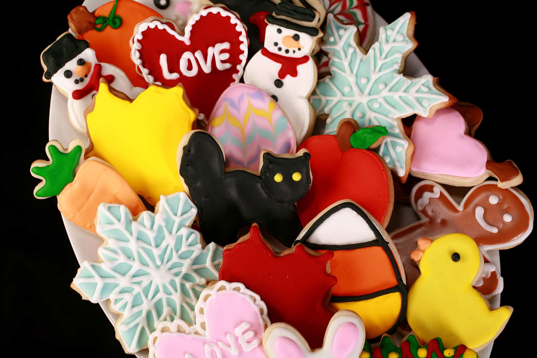 A plate of brightly colored cookies done up in a variety of themes - Halloween, Christmas, Easter, Valentine’s Day, etc.