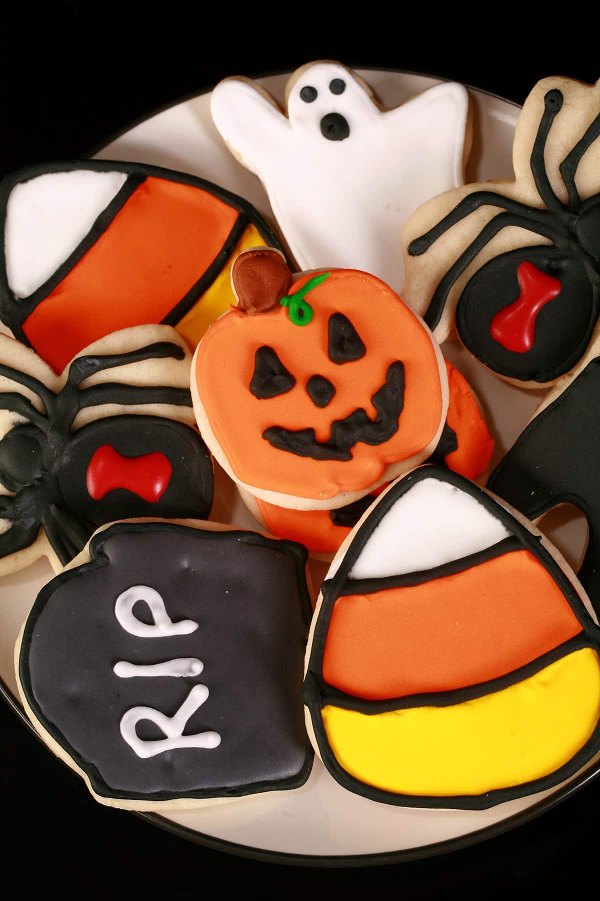 A plate of brightly colored Halloween themed decorated sugar cookies.