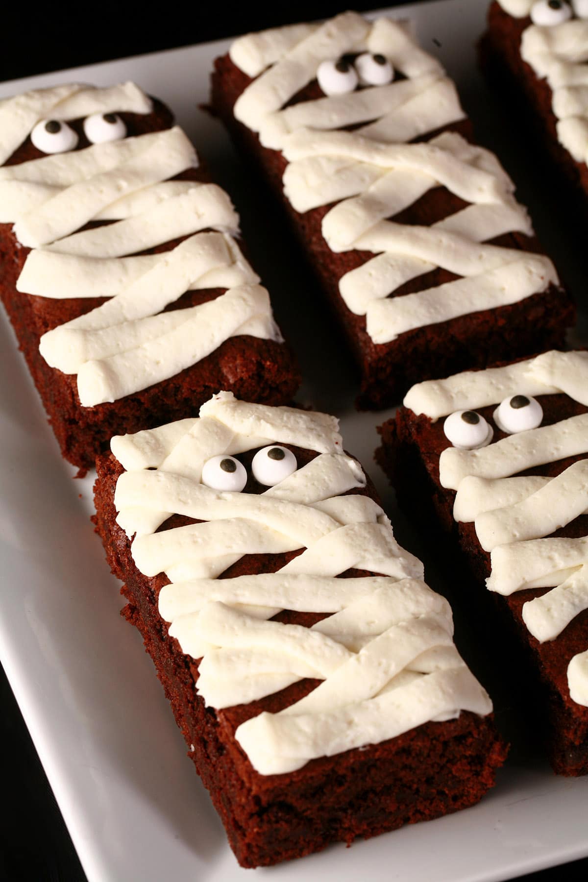 A plate of mummy brownies, with candy eyeballs.