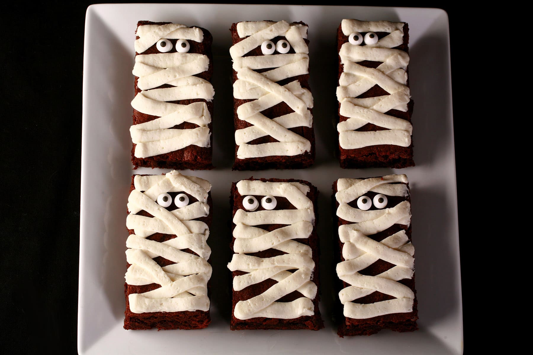 A plate of mummy brownies, with candy eyeballs.