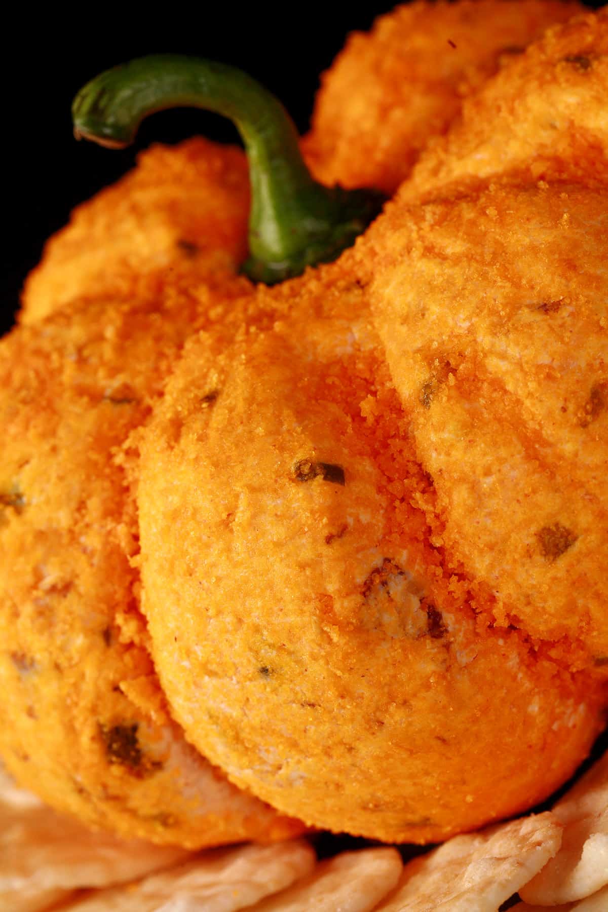 A bacon jalapeno pumpkin cheese ball on a plate of crackers.