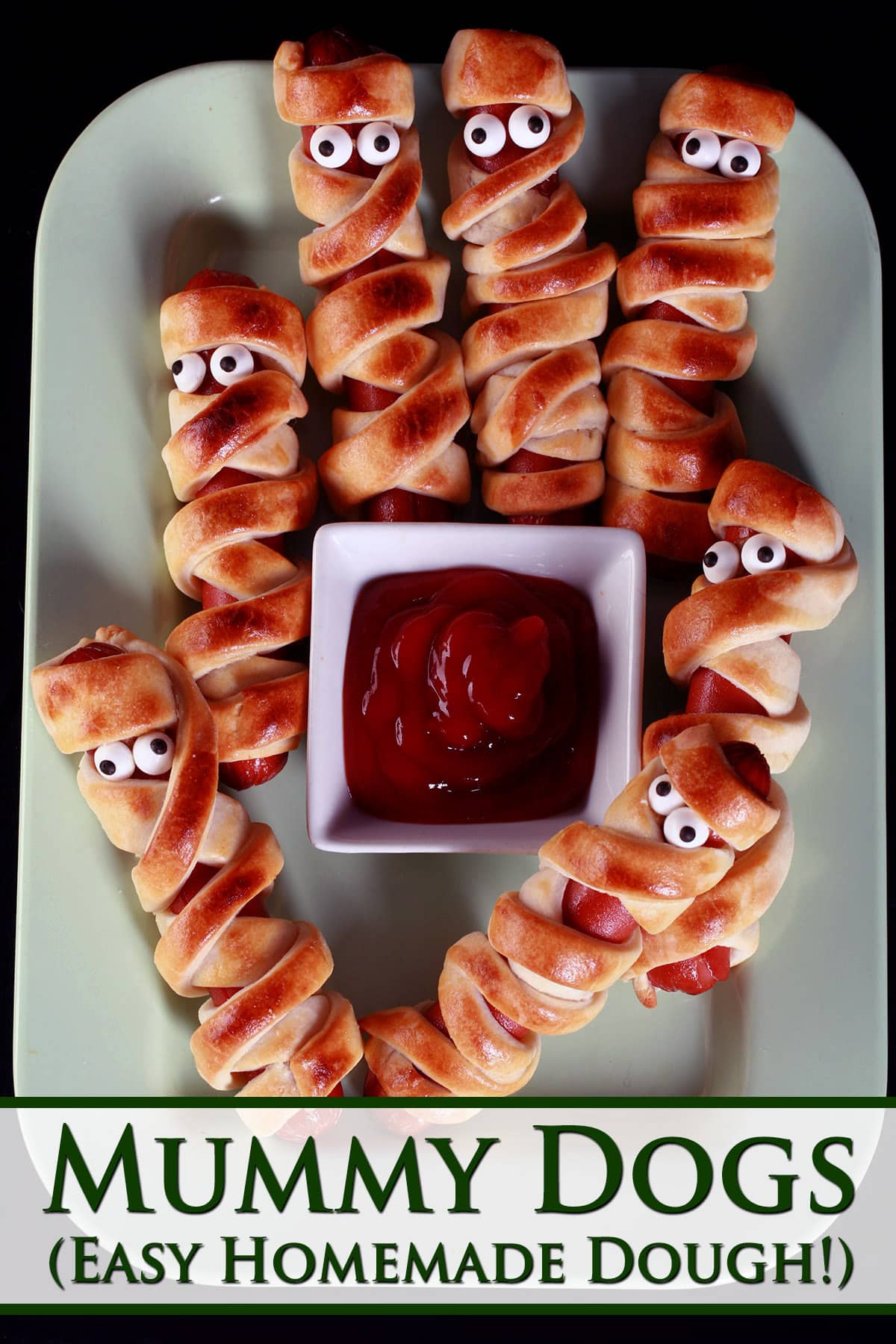 Several mummy dogs on a plate, each has 2 candy eyeballs.