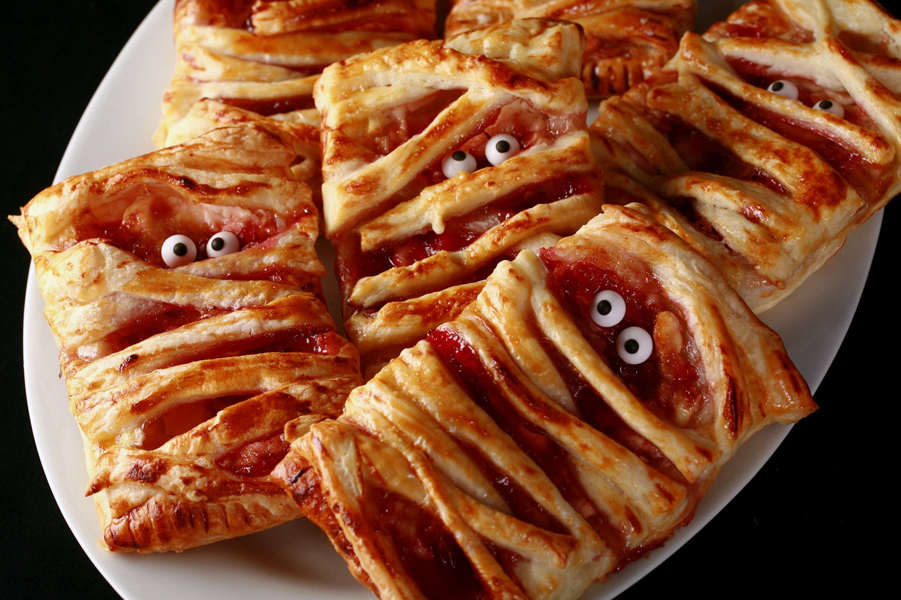 A plate of unglazed mummy pastries - a raspberry cream cheese danish.