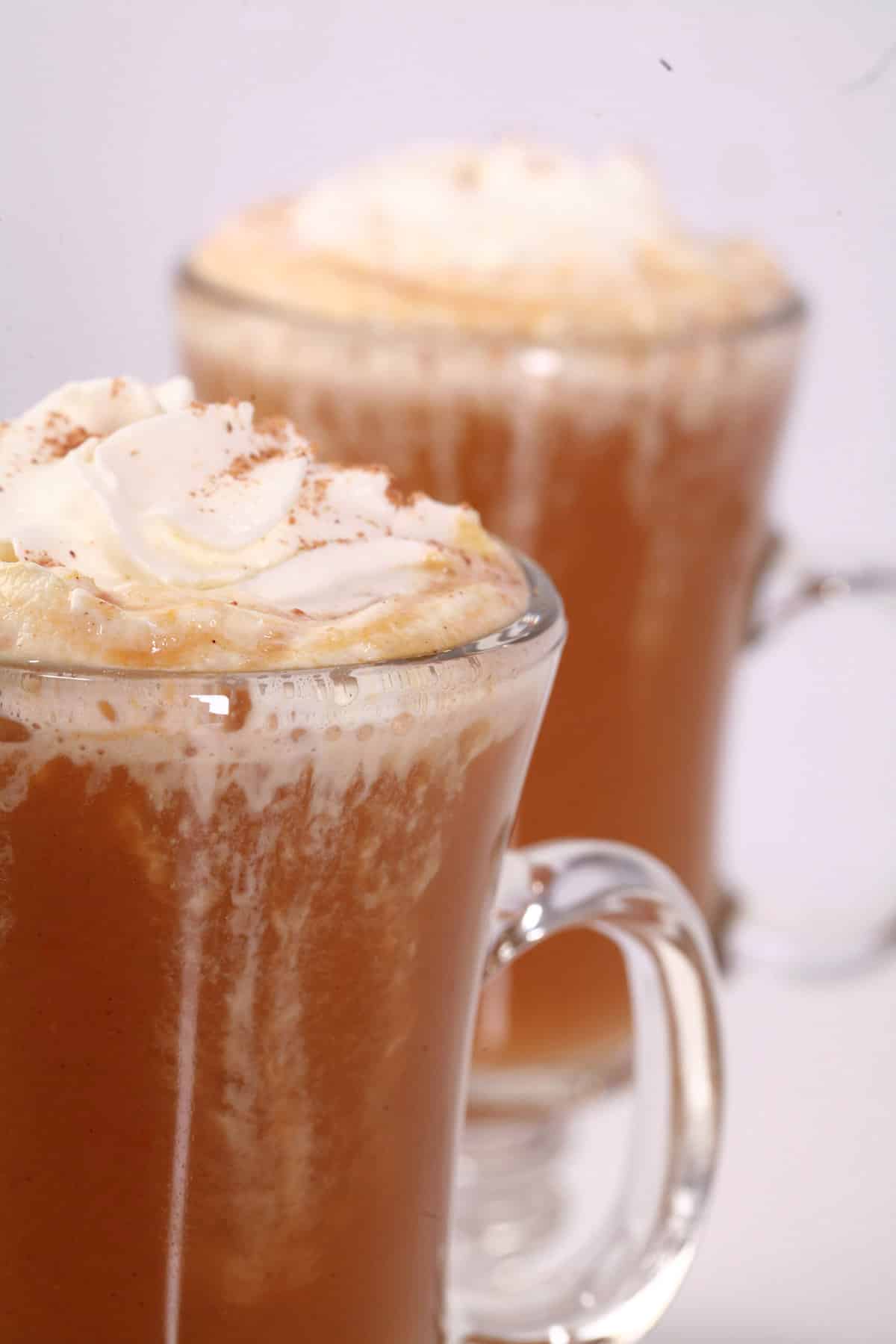 2 homemade pumpkin spice lattes, topped with whipped cream and nutmeg.