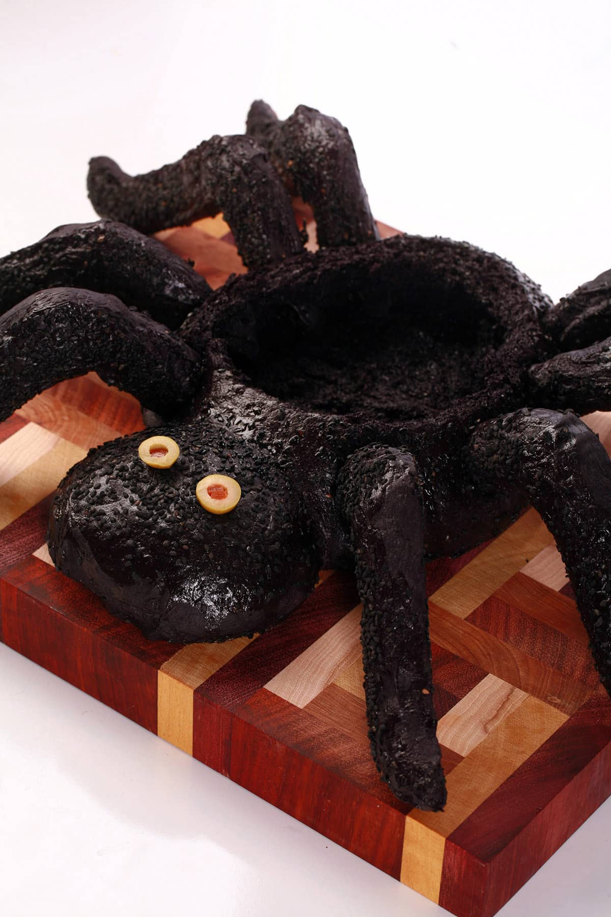 A black spider bread bowl on a wooden cutting board.