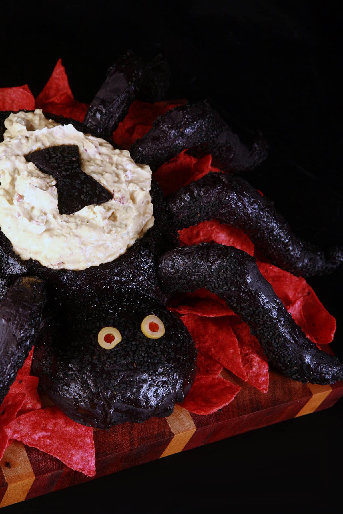 A Halloween bread bowl, shaped like a black spider and filled with dip.