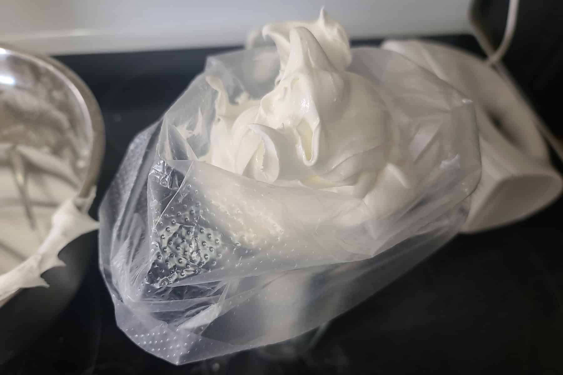 White royal icing being spooned into a pastry bag.