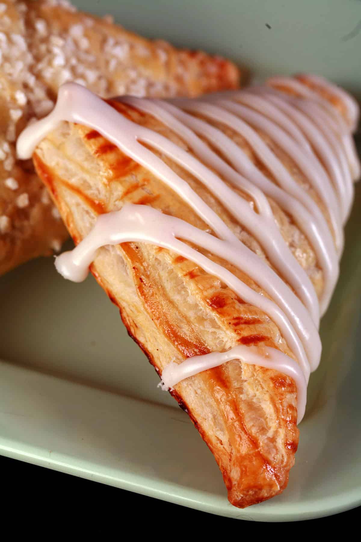 A close up view of a homemade apple turnover with a drizzled glaze.