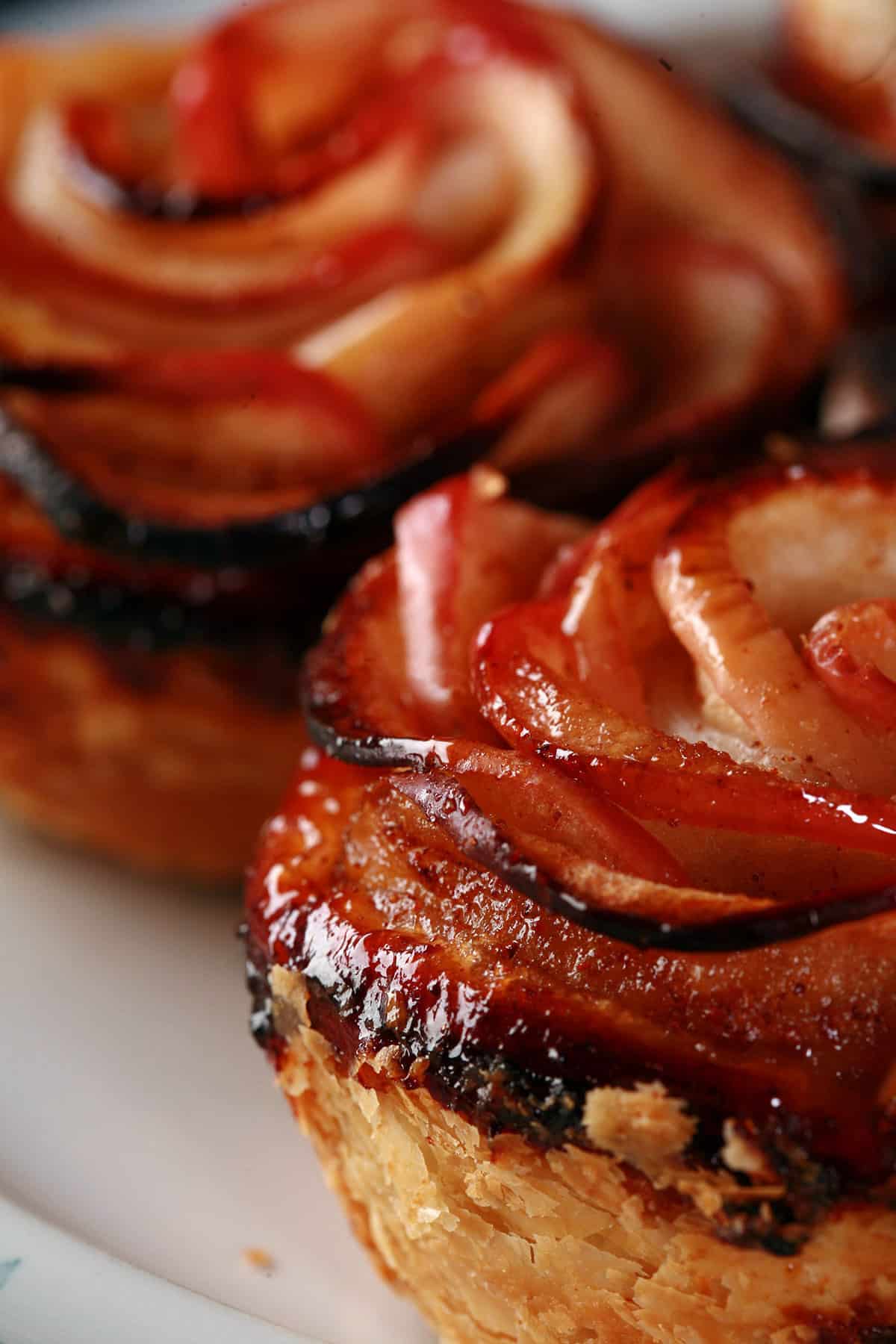 Maple syrup glazed apple roses with puff pastry, on a plate.