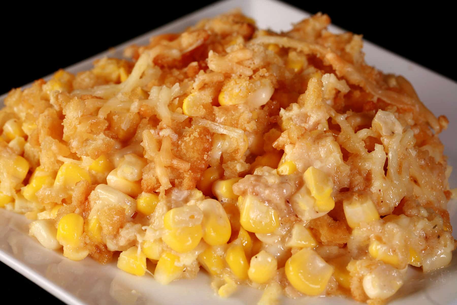 A white plate with a generous serving of homemade scalloped corn.