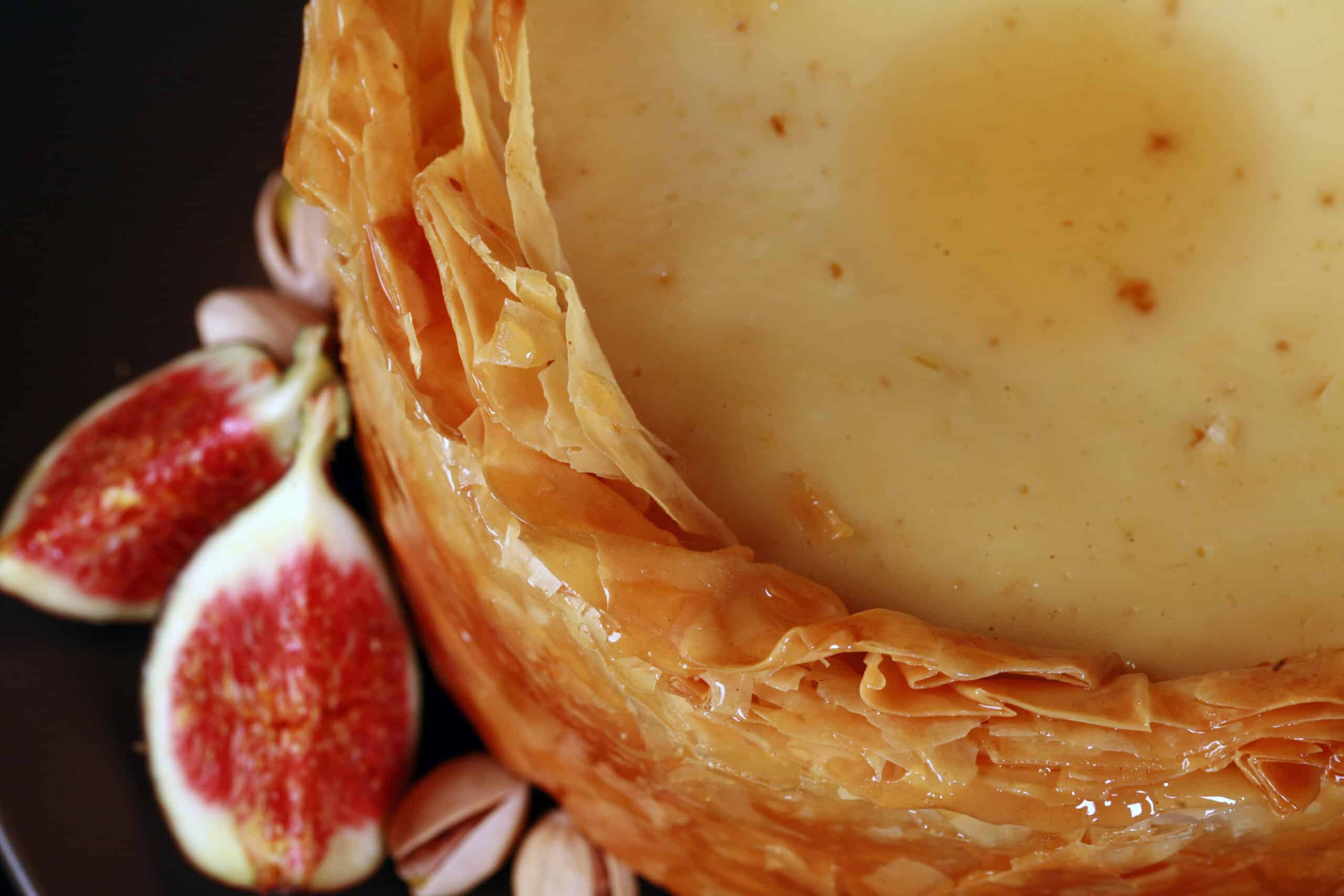 The top of a mini cheesecake. showing off flaky layers of phyllo pastry crust.