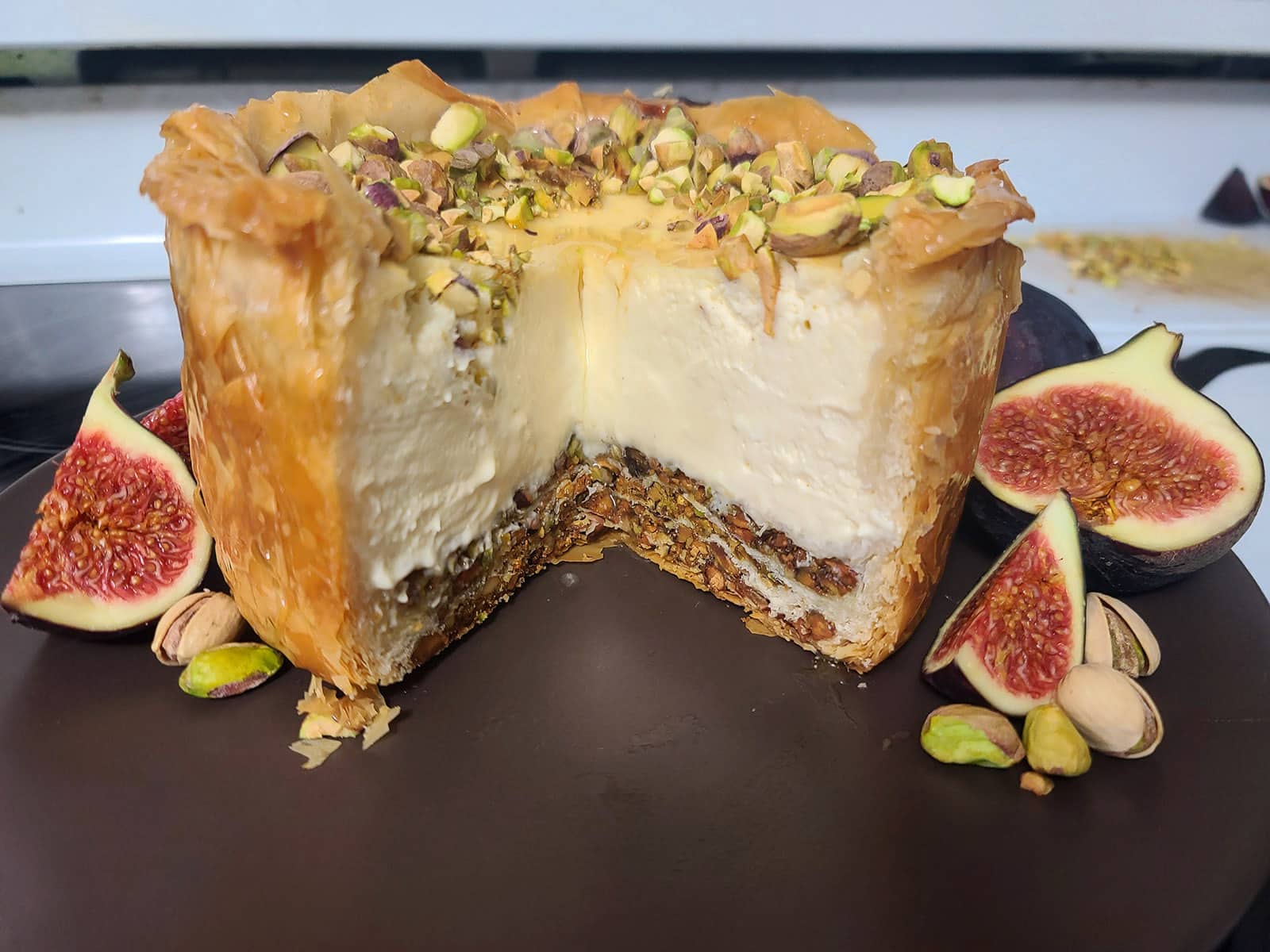The finished baklava cheesecake, on a stovetop, with figs around it.