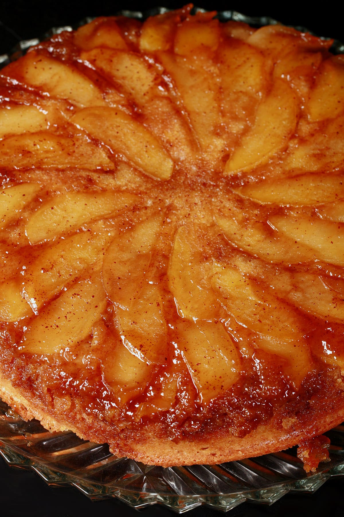 A close up view of a whole uncut apple upside down cake.