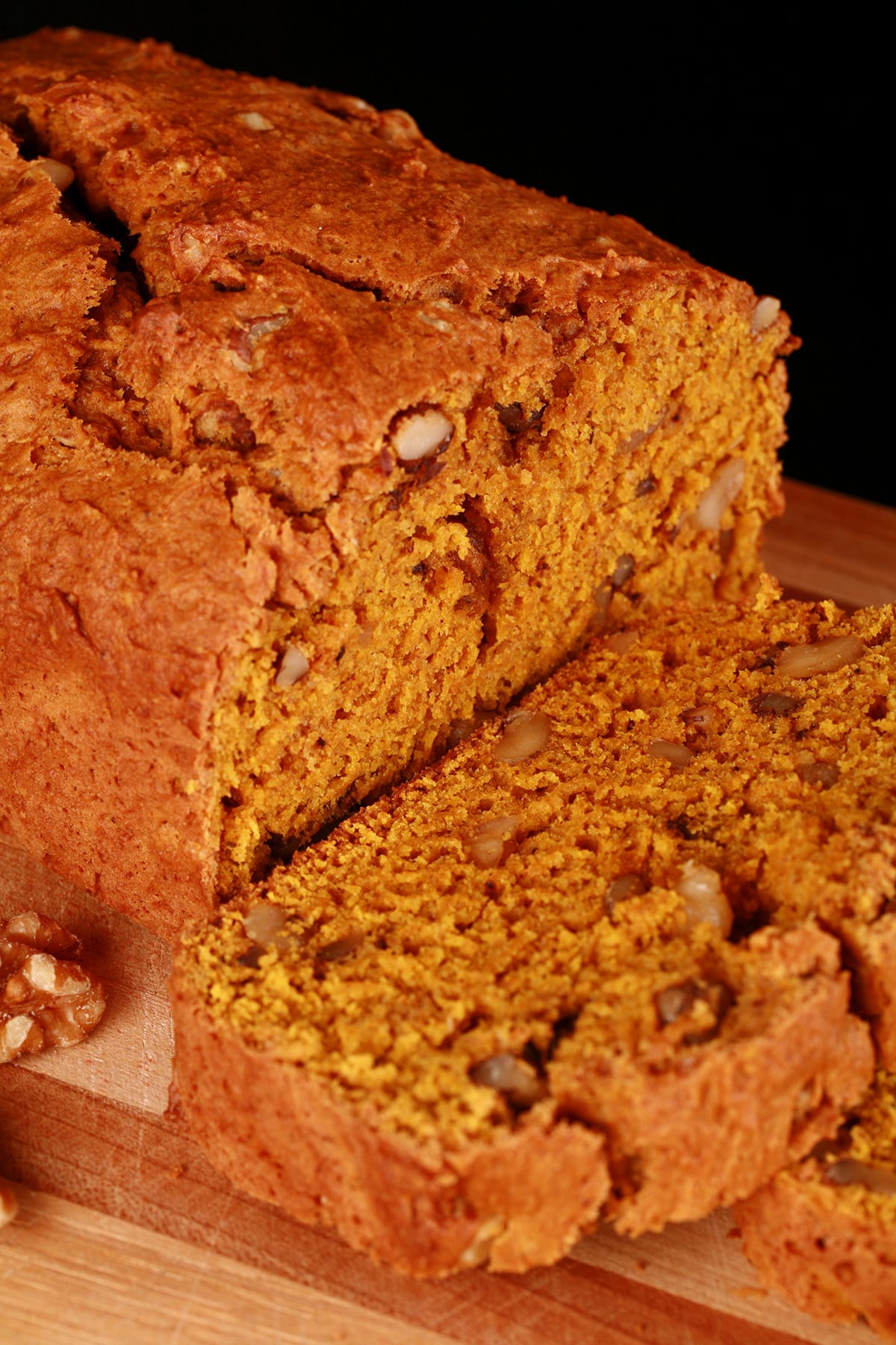 A loaf of sliced pumpkin quick bread on a cutting board.