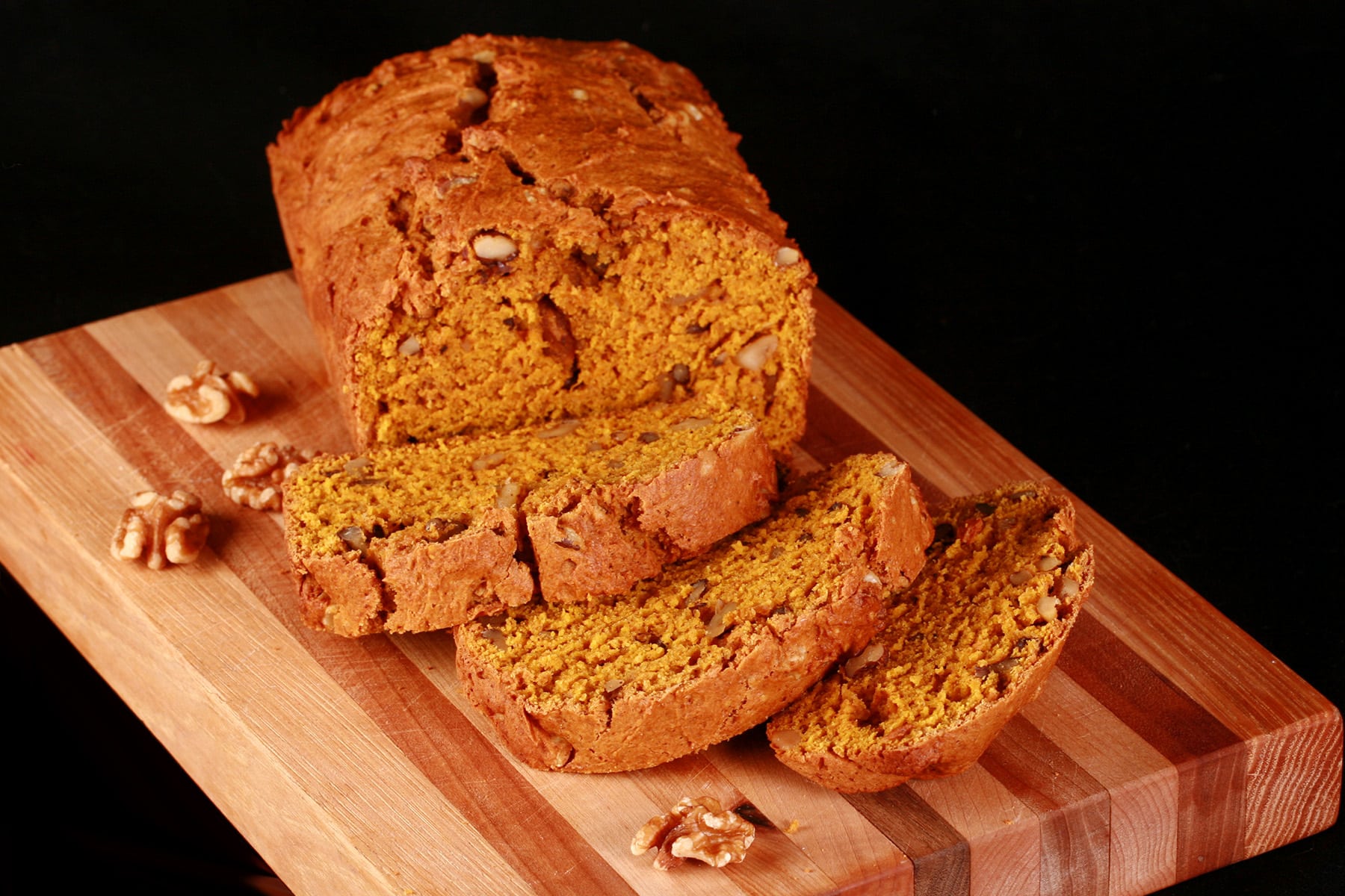 A loaf of sliced pumpkin quick bread on a cutting board.