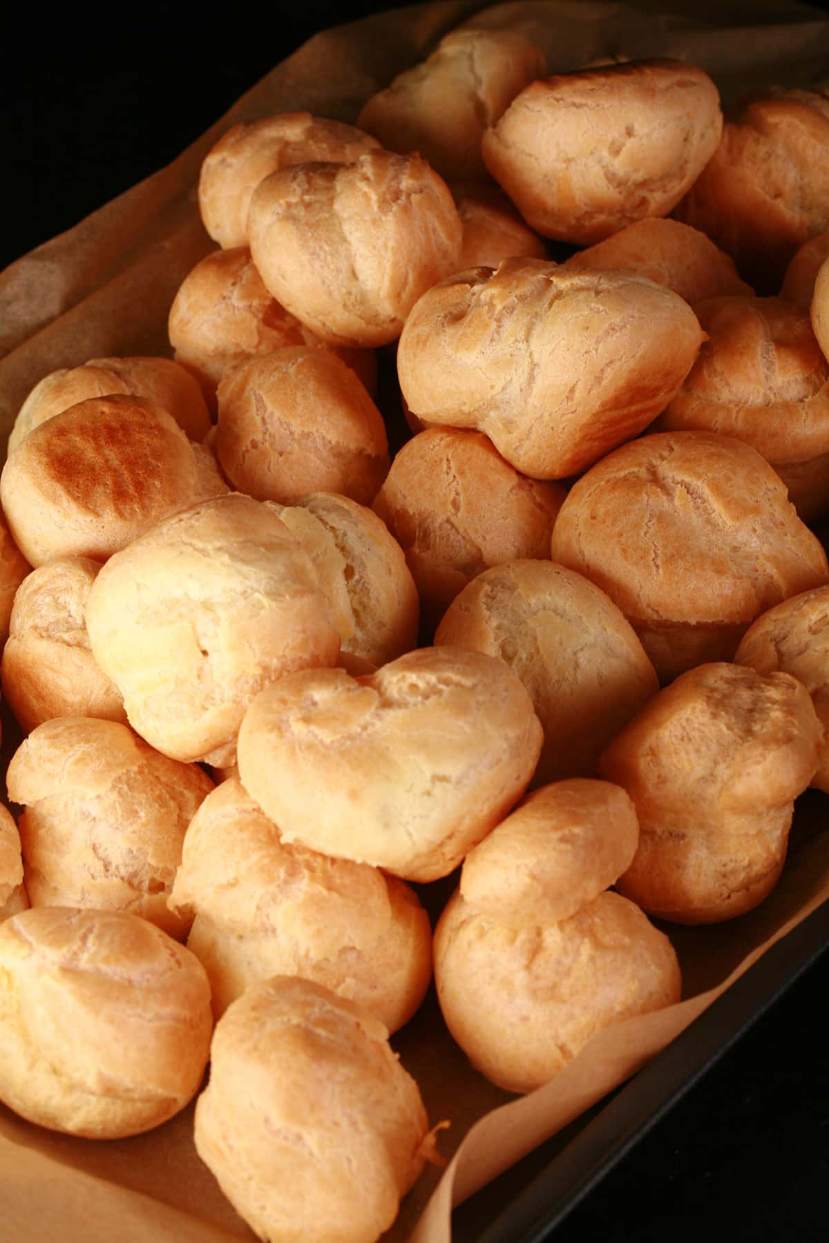 A tray of unfilled profiterole shells.