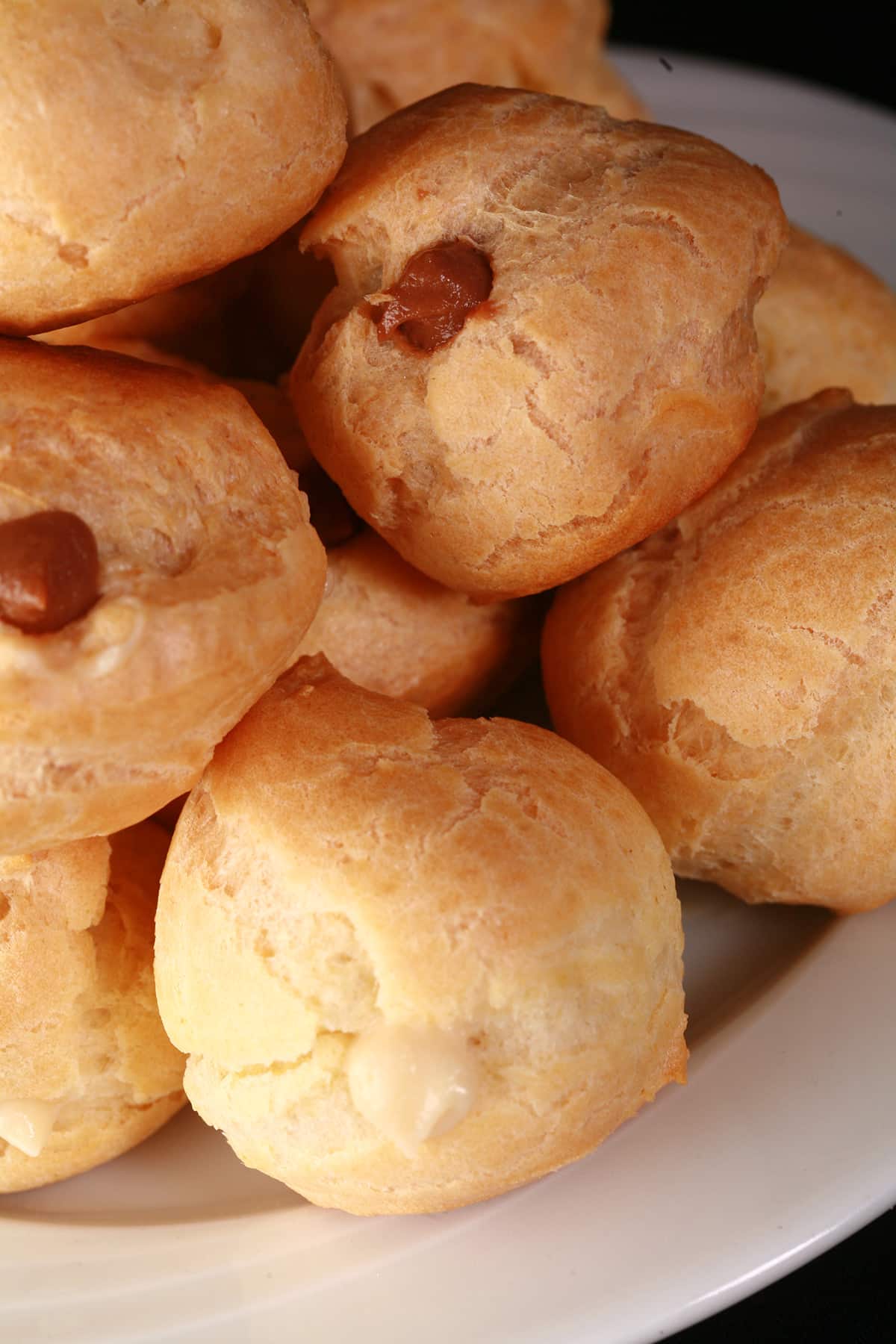 A pile of vanilla and chocolate cream filled profiteroles on a plate.