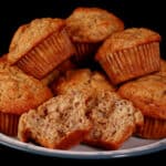 A plate of banana walnut muffins with one broken in half.