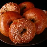A plate of banana nut bagels, some with a sugar topping.