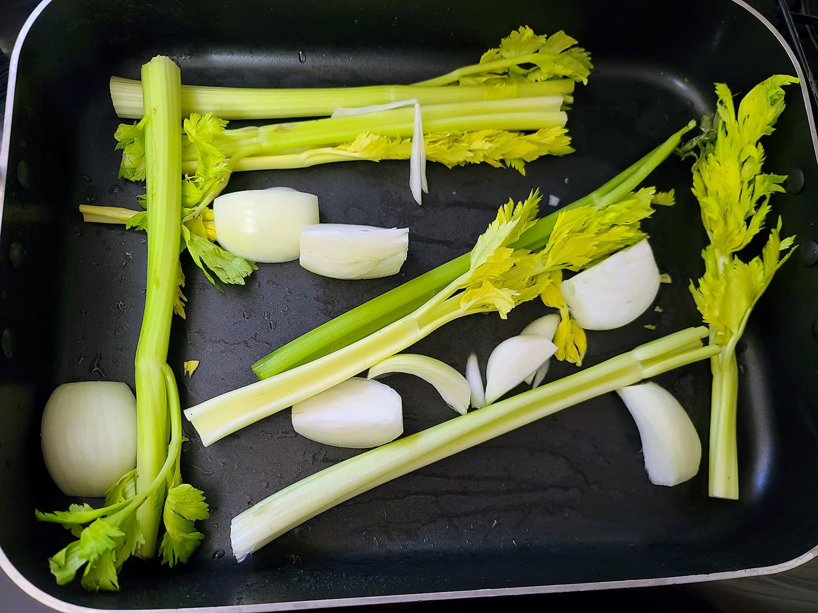 Onions and celery in a roasting pan.