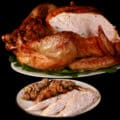 A plate of sliced turkey and stuffing in front of a roasted turkey.