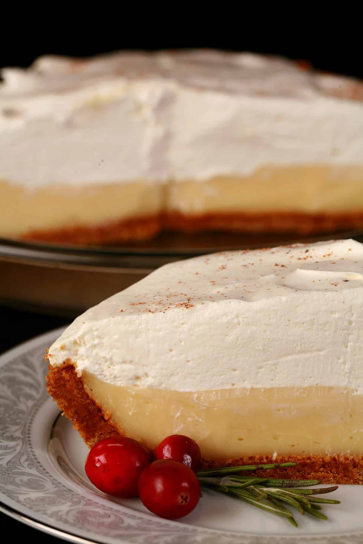 A slice of eggnog pie, with the rest of the pie behind it.