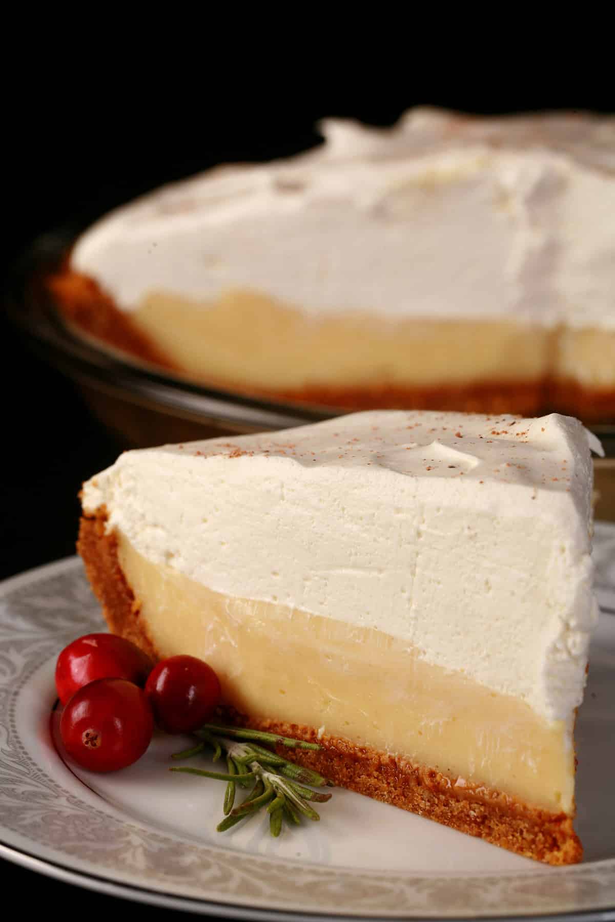 A slice of eggnog cream pie, with the rest of the pie behind it.