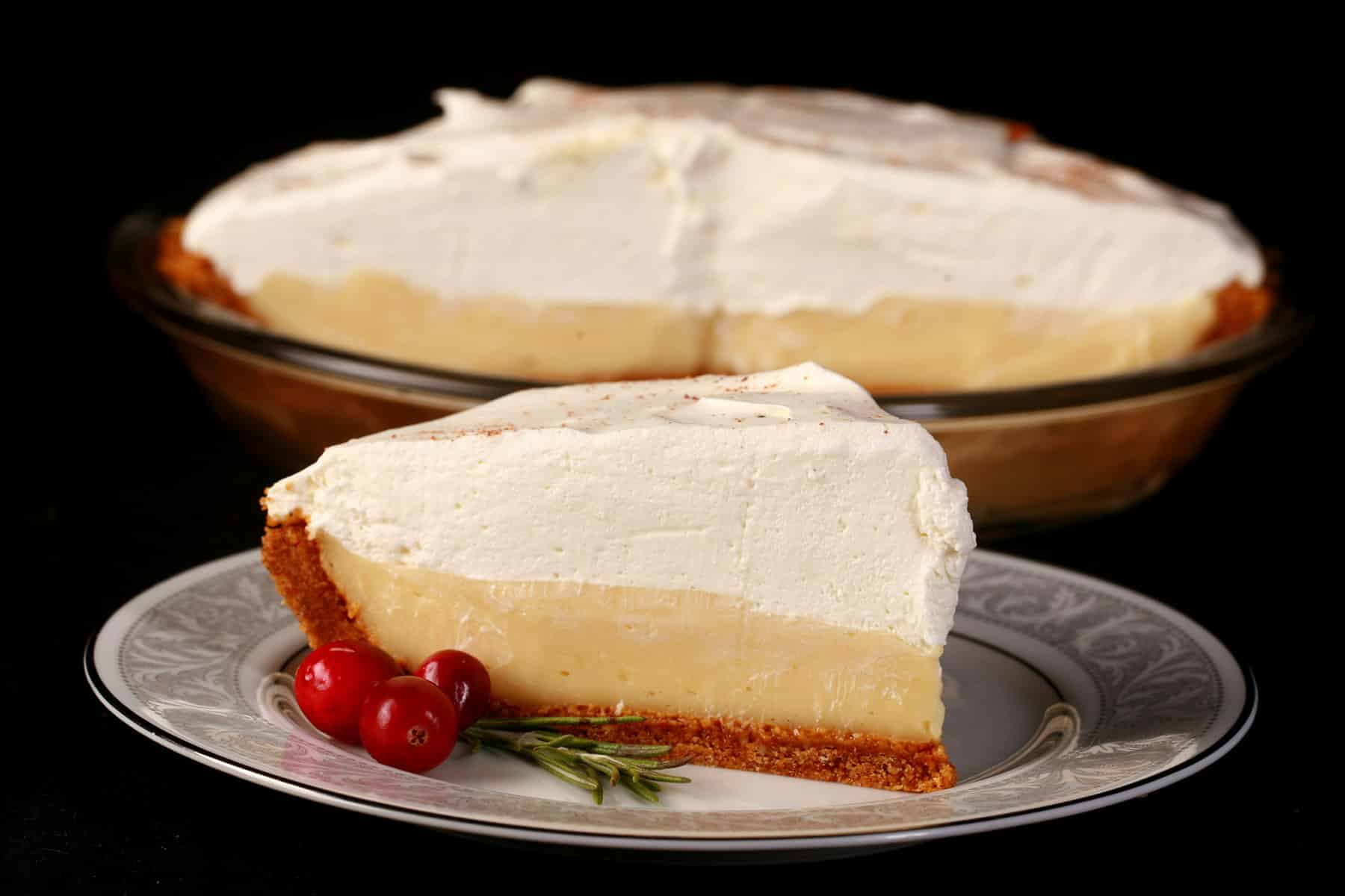A slice of eggnog cream pie, with the rest of the pie behind it.