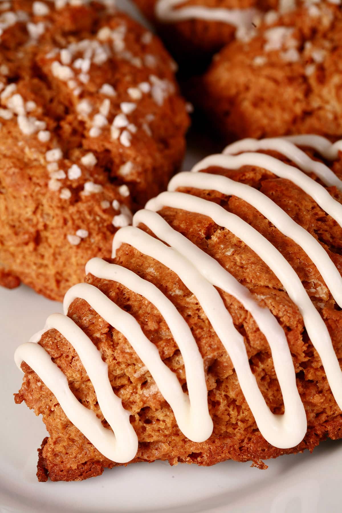 A plate of gingerbread scones. Some have sugar topping, others are drizzled with frosting.