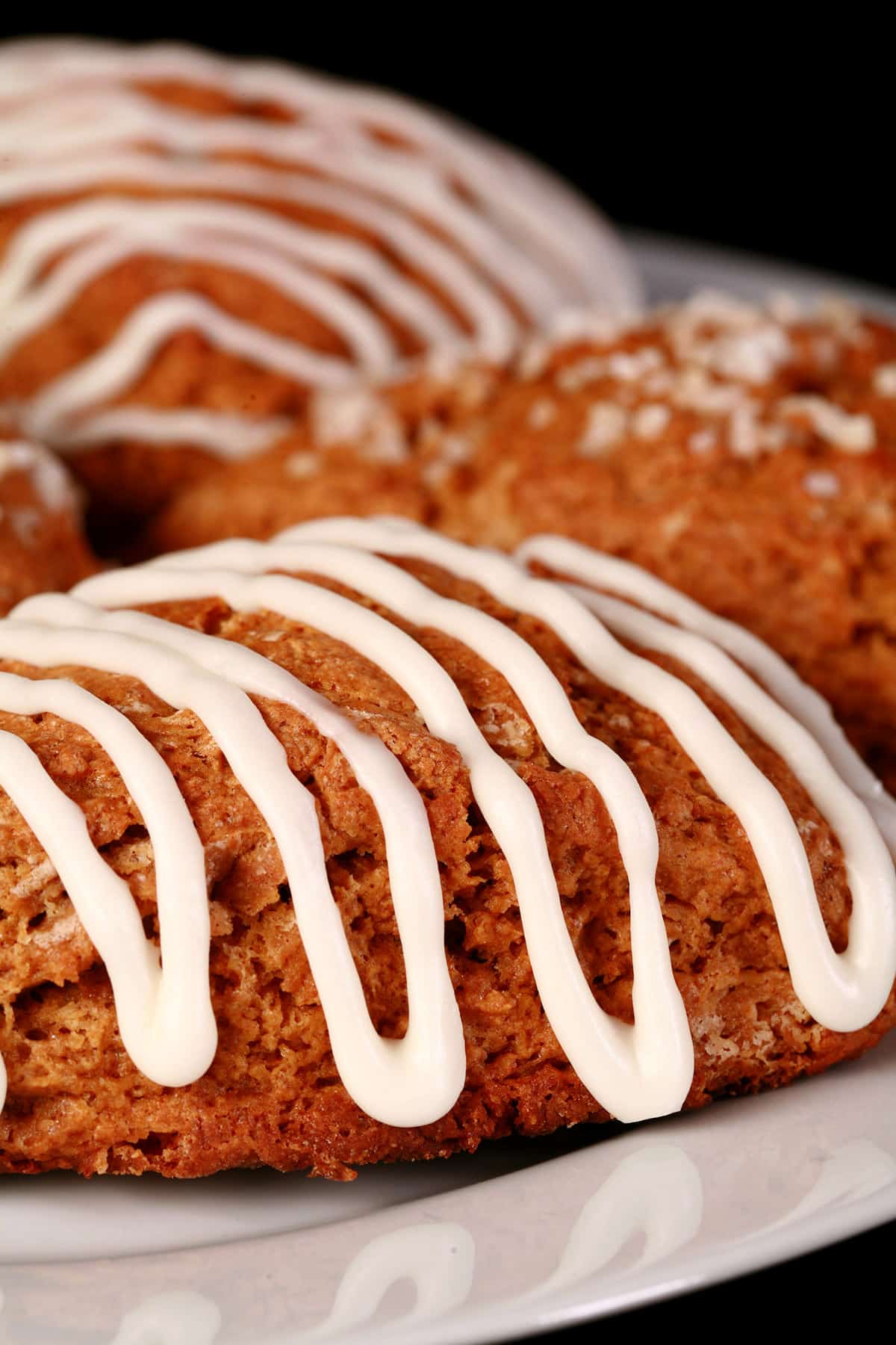 A plate of gingerbread scones. Some have sugar topping, others are drizzled with glaze.