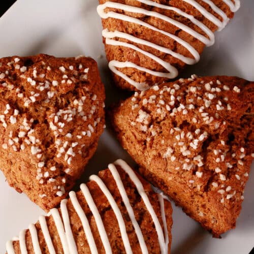 A plate of gingerbread scones. Some have sugar topping, others are drizzled with frosting.