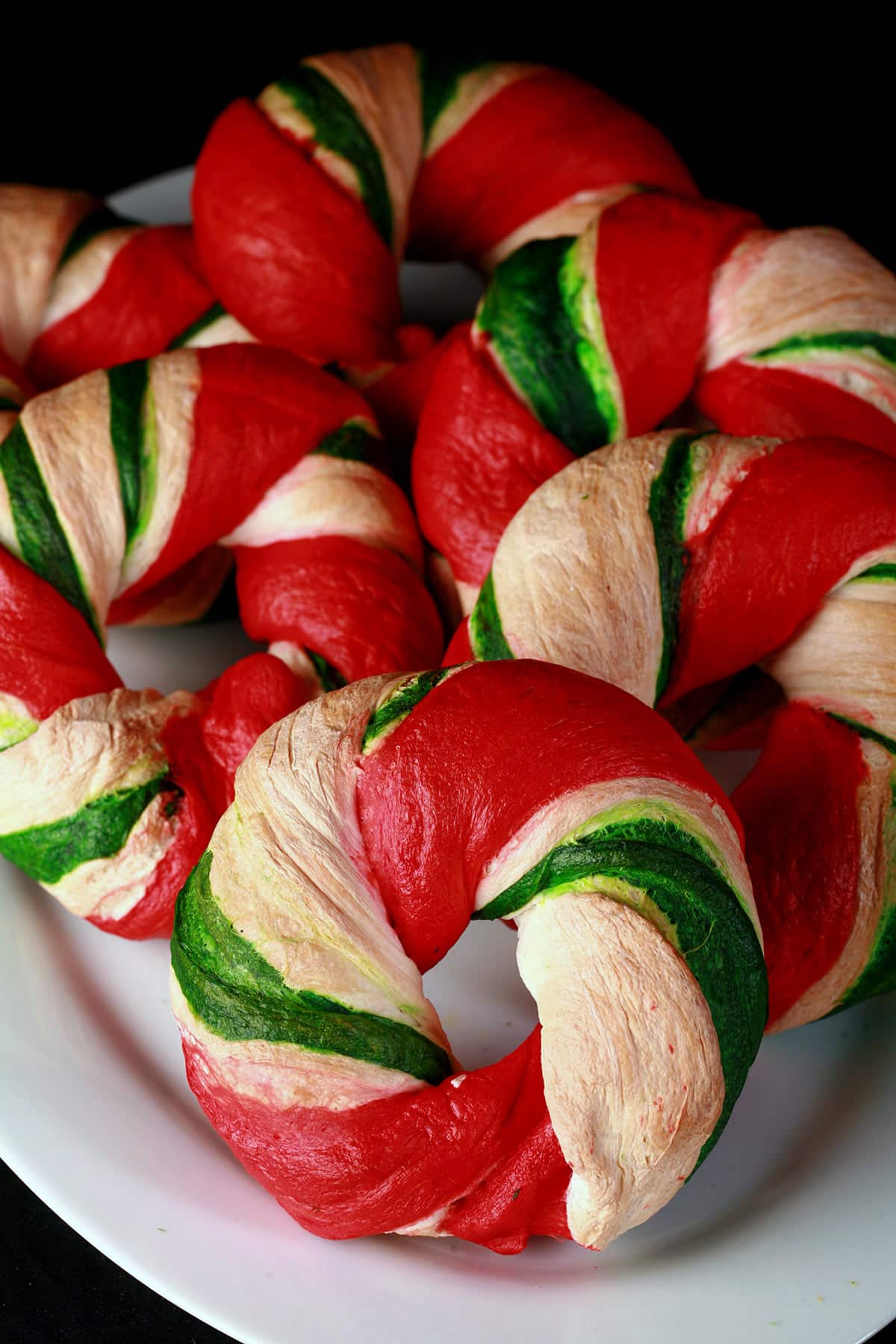 Several candy cane style Christmas bagels on a plate.