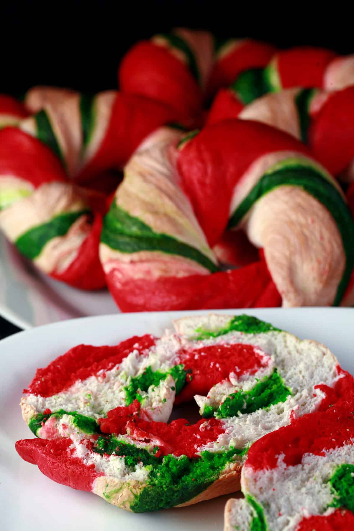 Several candy cane style Christmas bagels, with a cut one on a plate.