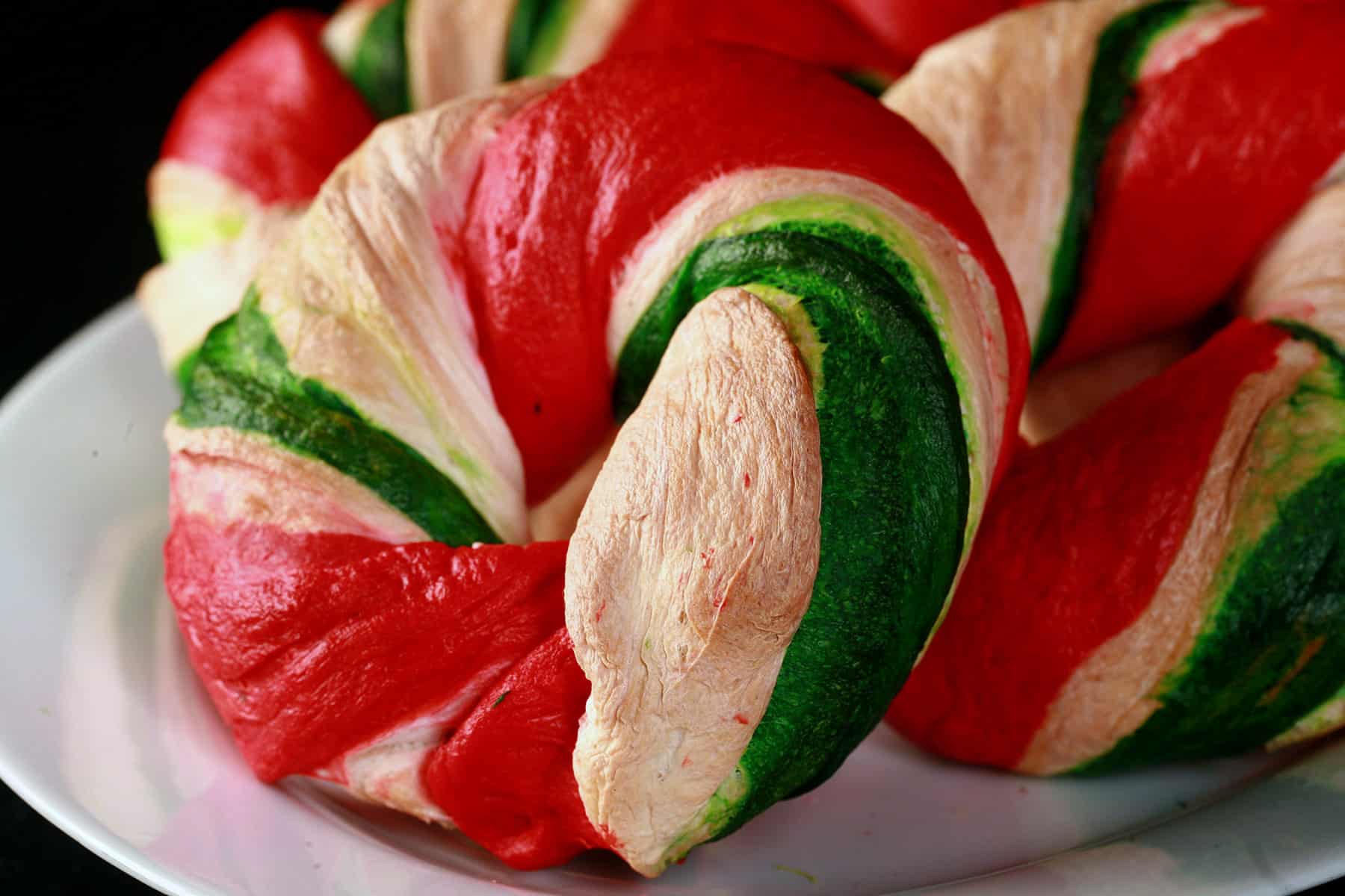 Several red, white, and green Candy cane bagels on a plate.