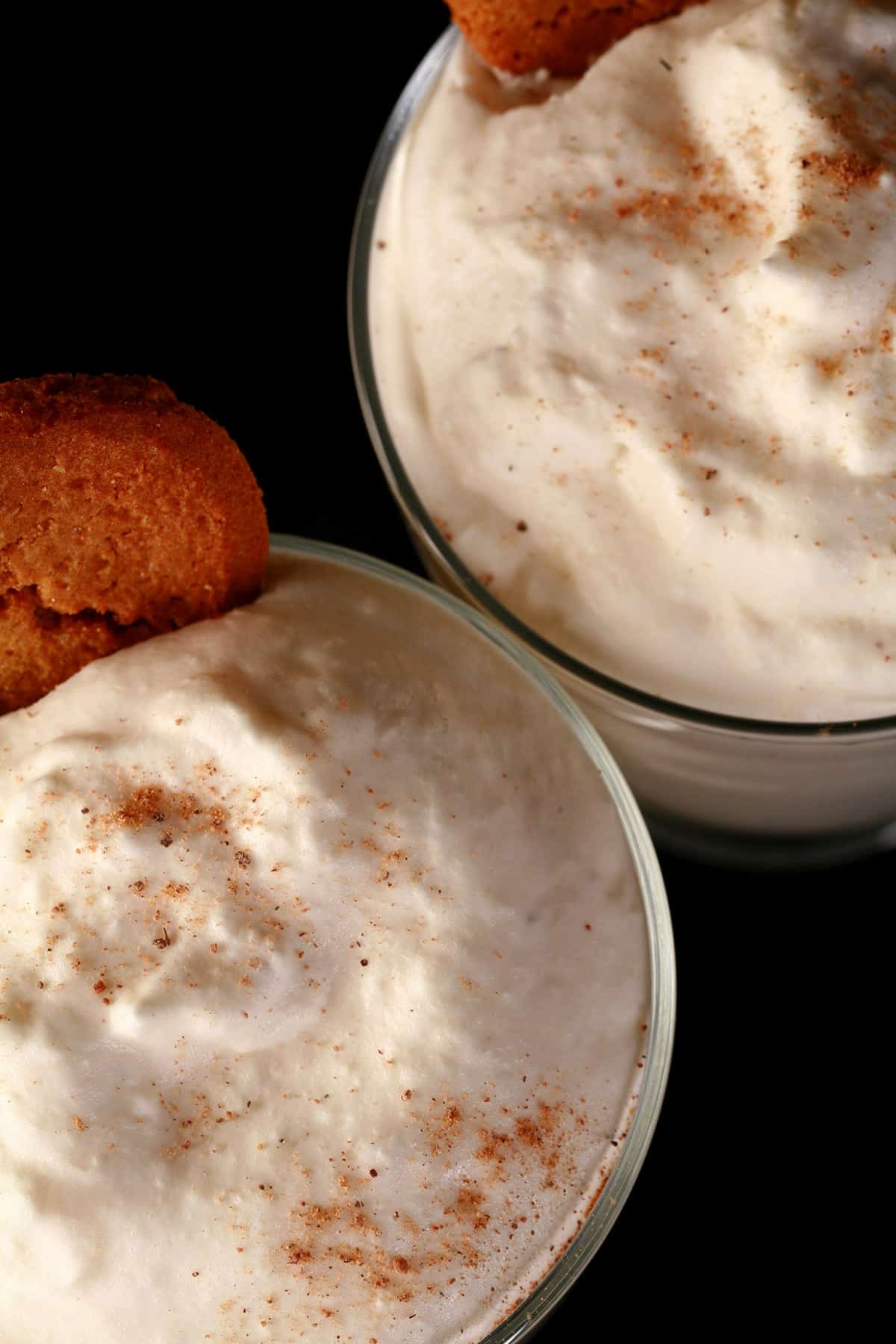 2 glasses of traditional style eggnog mousse, with nutmeg and gingersnap cookie garnish.