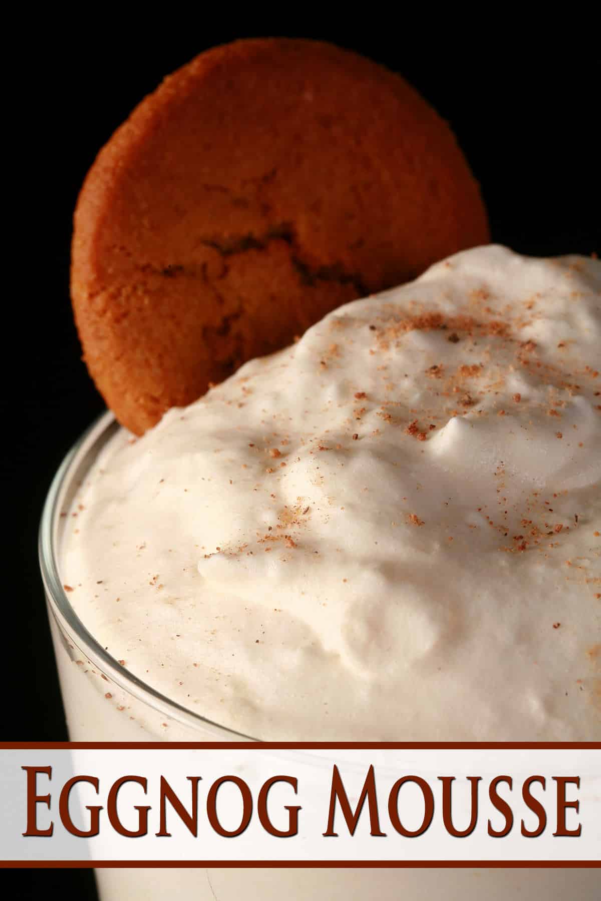 A close up photo of a glass eggnog mousse, with nutmeg and gingersnap cookie garnish.